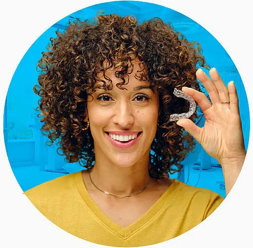 A person smiles brightly, proudly displaying an Invisalign aligner against a serene blue background in Liberty Township or Hamilton, OH