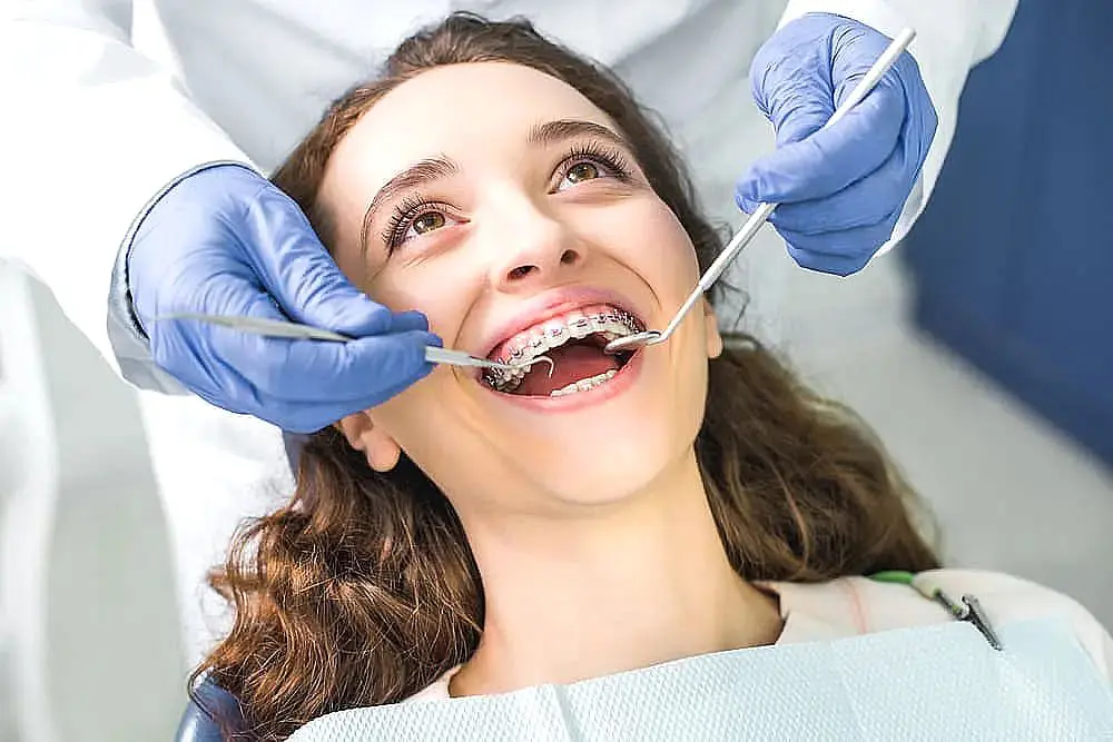 A person benefiting from a braces payment plan is undergoing a dental check-up, as the dentist carefully uses tools to examine their teeth in Liberty Township or Hamilton, OH