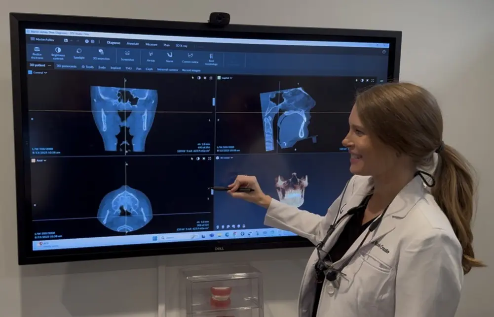 Dr. Nicole Crasto, DDS, MS: Orthodontist in Liberty Township, OH A woman in a lab coat points at dental X-rays on a monitor at Queen City Orthodontics in Hamilton, OH.