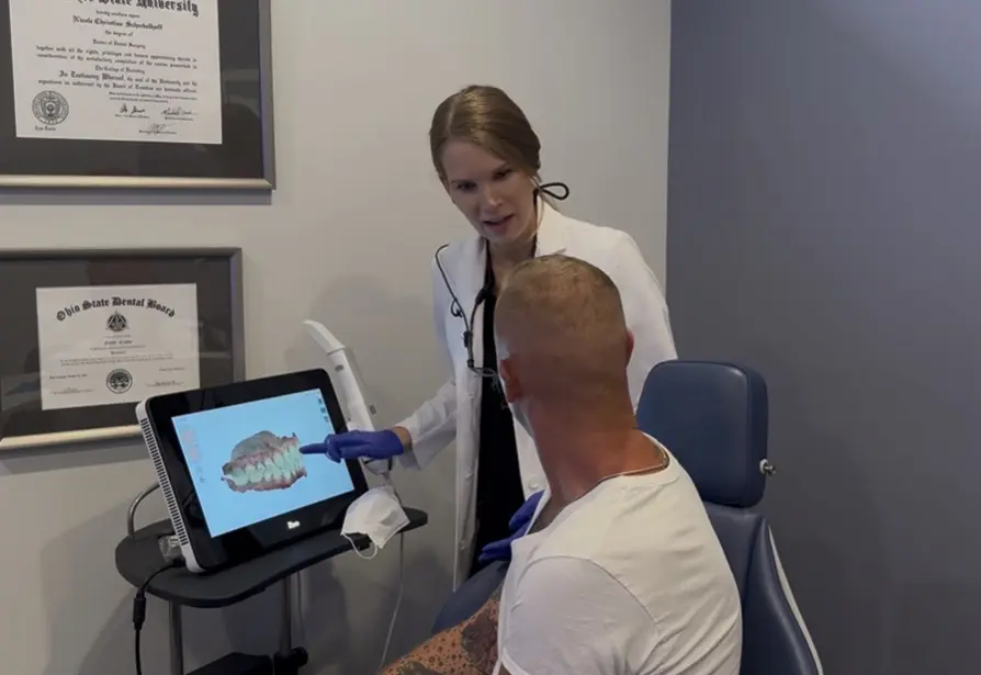 Dr. Nicole Crasto, DDS, MS: Orthodontist in Liberty Township, OH In a Queen City Orthodontics office in Liberty Township, OH, a dentist shows a dental scan to a patient.
