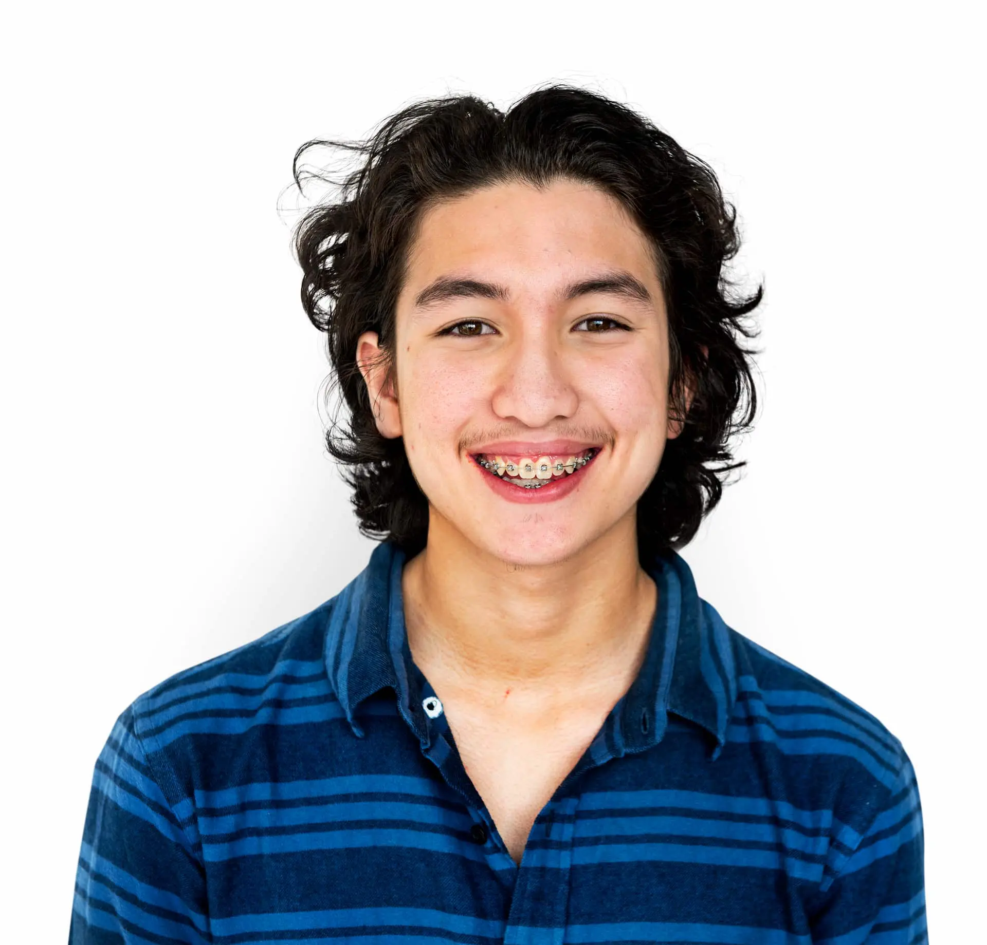 Smiling young person with long dark hair and braces, wearing a blue striped shirt at Queen City Orthodontics in Liberty Township or Hamilton, OH.